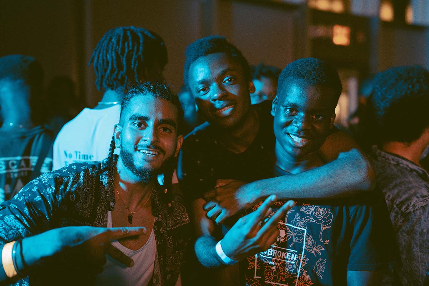 Group of students lighted by teal light, smiling at the camera